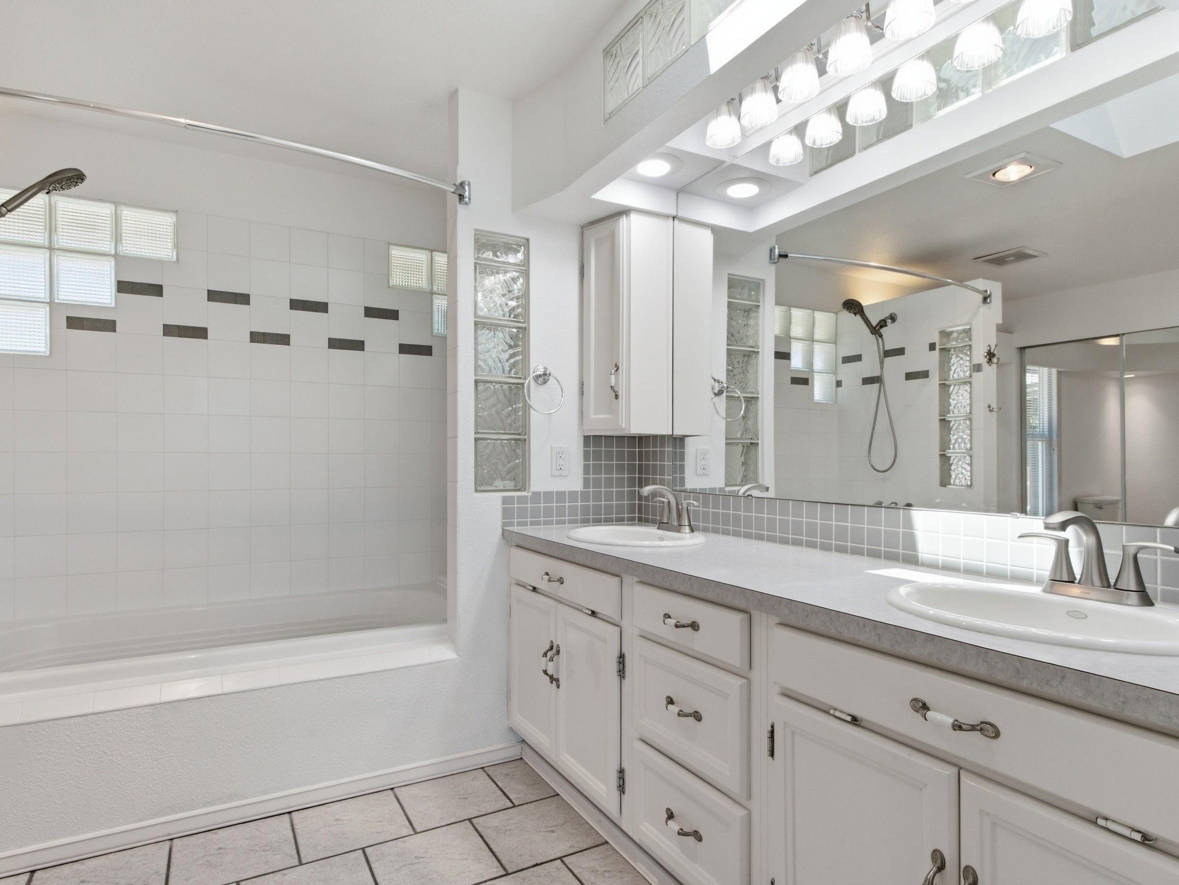 Wide real estate photograph of a bright primary bathroom